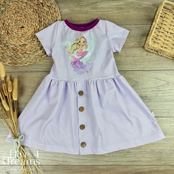 Handmade Kinderkleid f&uuml;r M&auml;dchen mit einer Meerjungfrau auf dem Oberteil und einer verspielten Knopfleiste im Rockteil. Mitwachsend & aus weichem Jersey gen&auml;ht.